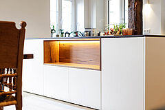 Kontrast aus modernem Küchendesign und Altholzoptik, mit Fokus auf die zentrale Kücheninsel.