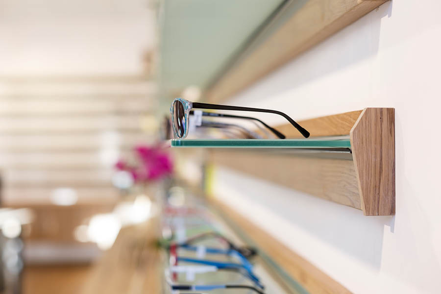 Wanddisplay mit Holzprofil und Glasablage zur Brillenpräsentation; feine Fräsung, klare Linien, Beispiel für schlanke Regallösung. Aktuelles – Trends – News im November 2025 | Möbeltischlerei woodendesign | Tischlerei Möbeltischler Möbelmanufaktur Hamburg