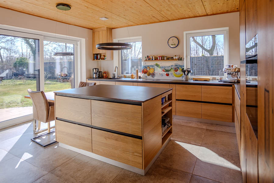 mit Sitzgelegenheit durch integrierten Tisch, Fronten aus Altholz | Kücheninseln, auch Küchenblock oder freistehende Kochinsel genannt, sind das Zentrum moderner Küchen. Die Möbeltischlerei woodendesign, Ihr Küchenexperte / Küchenprofi in Hamburg berät Sie gern.