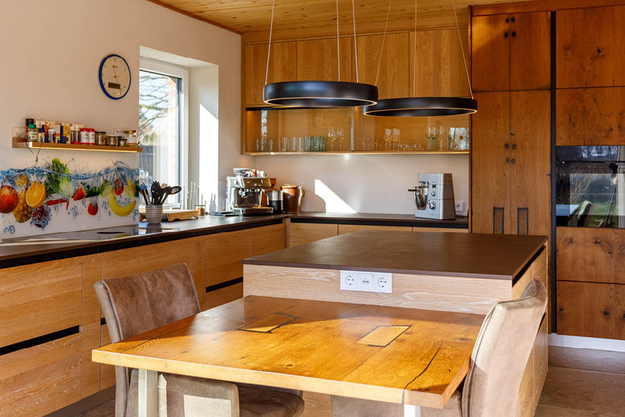 Massivholzküche von Küchenhersteller woodendesign mit Kücheninsel und beleuchteten Hängeschränken | Möbeltischlerei woodendesign aus Hamburg